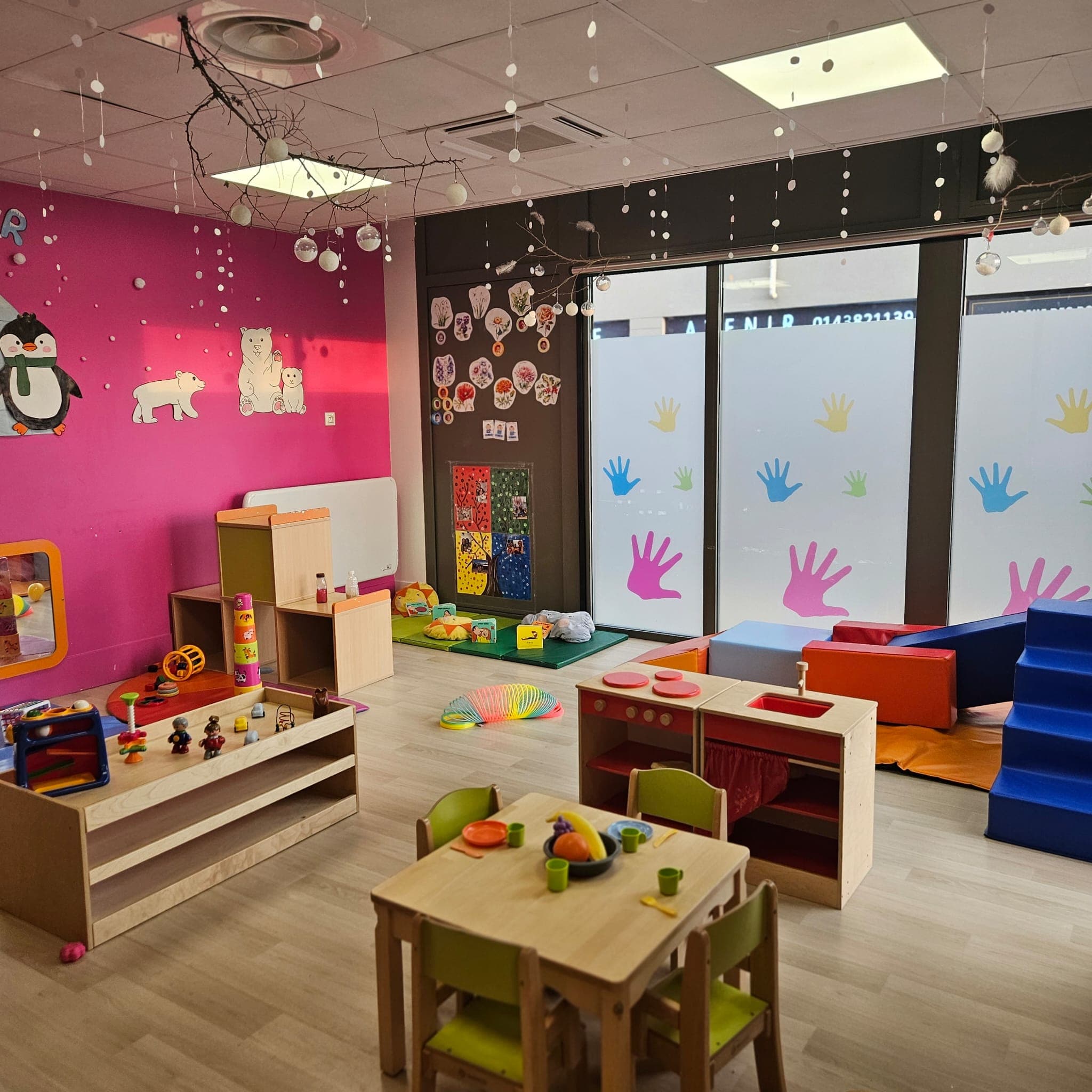 Salle principale de la crèche Efferv'sens avec ses murs fuchsia, jouets et mobilier coloré